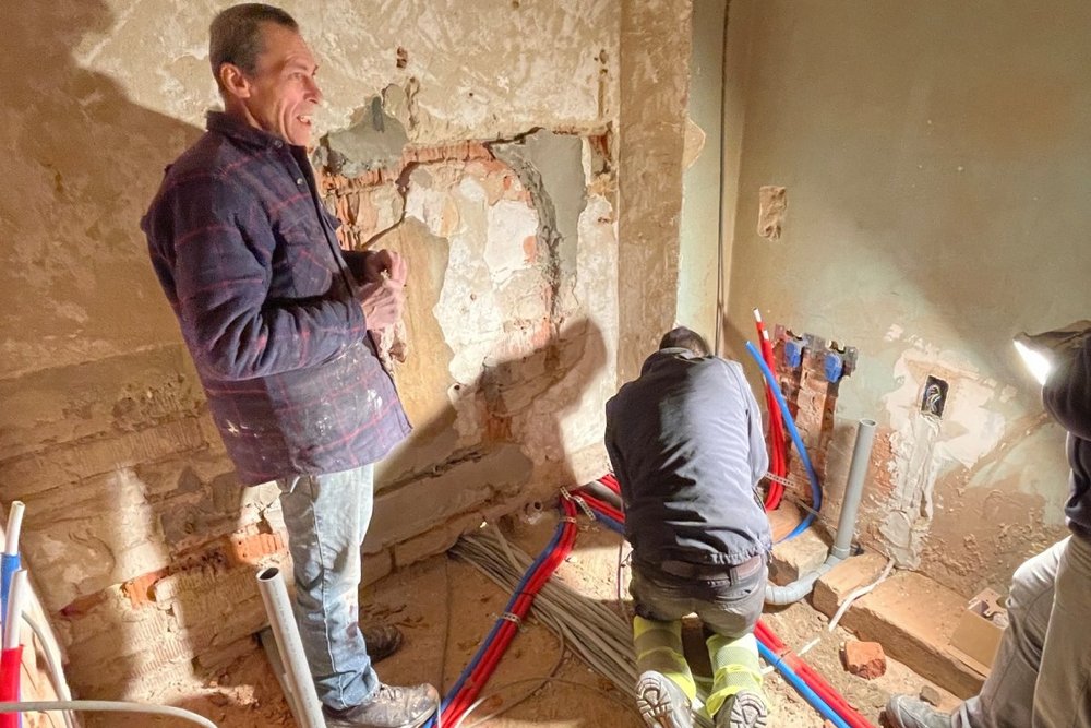 Zwei Arbeiter beim Verlegen von Kabeln im Rohbau