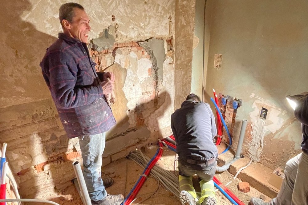 Zwei Arbeiter beim Verlegen von Kabeln im Rohbau