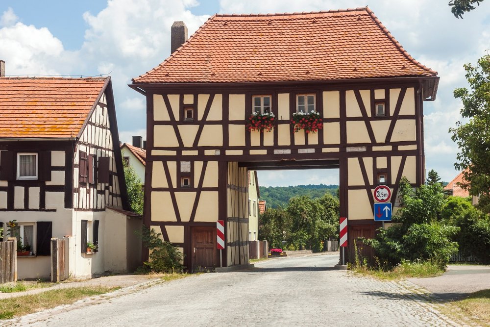 Altes Fachwerkhaus in Form eines Tores durch das eine Straße führt