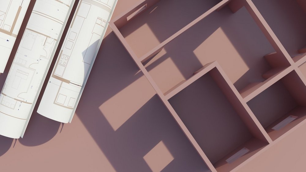 Holzmodell eines Hauses neben aufgerollten Bauplänen