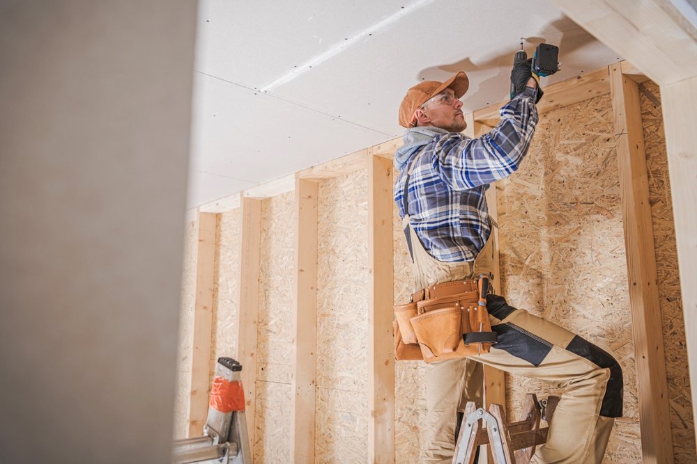 Arbeiter schraubt Trockenbauplatten an der Decke fest
